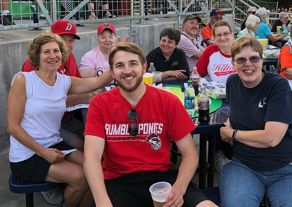 Alumni sitting by the baseball field at Night at the Rumble Ponies