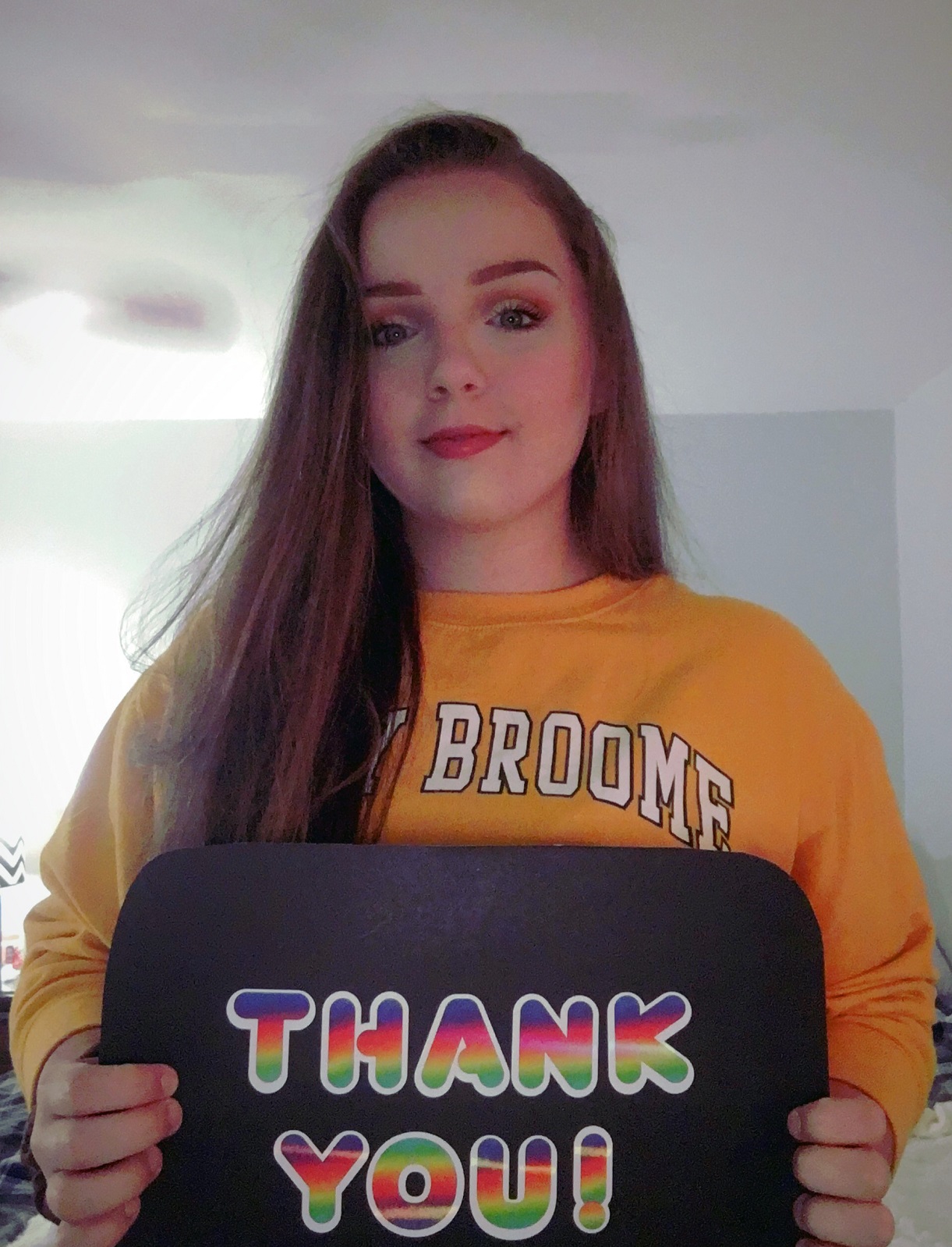 Haley holds a 'Thank You' sign and smiles.
