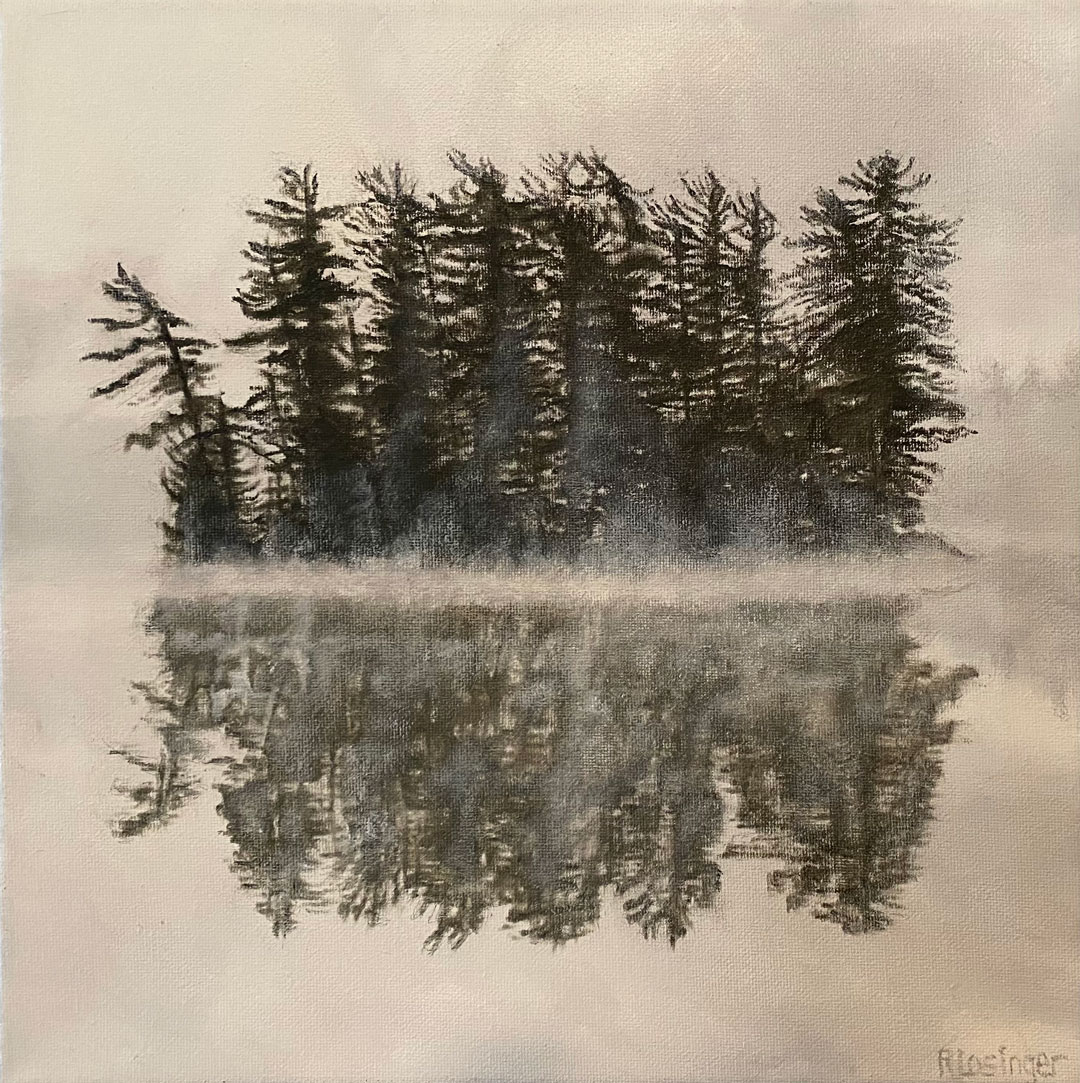 A small island of trees reflecting on a hazy foggy morning pond.