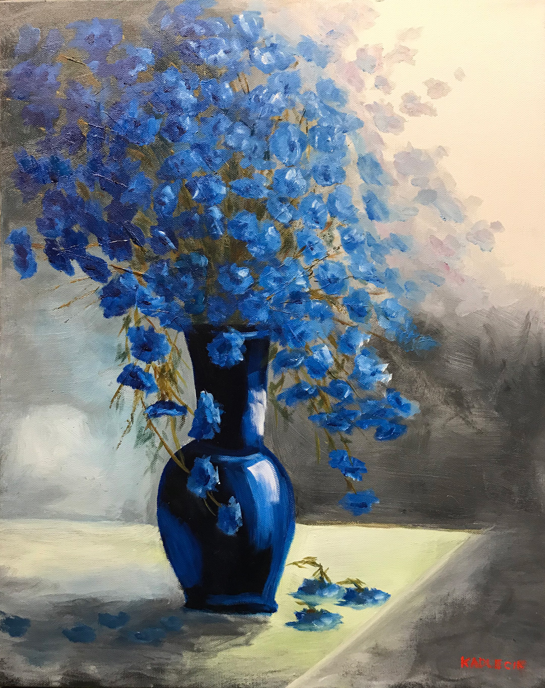 A blue vase filled with blue blossoms on a table.