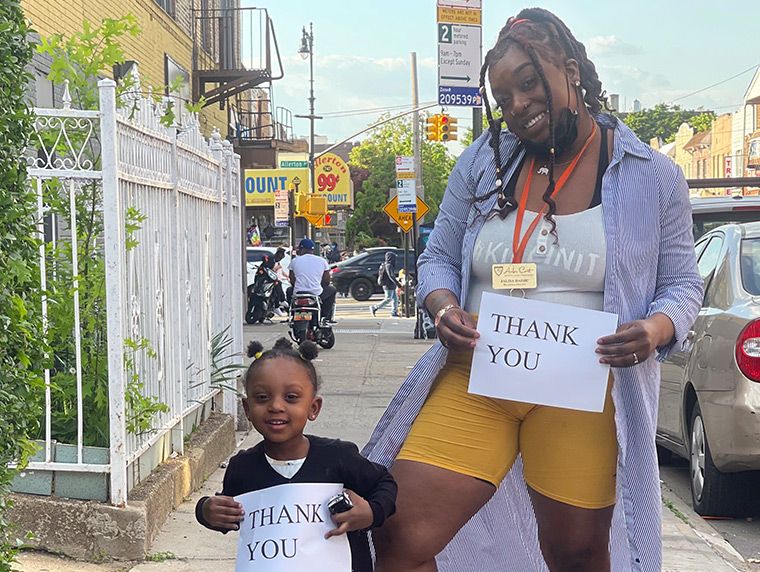 Jalisa and her toddler daughter hold up 'thank you' signs.