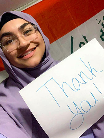 Aisha Ismail grins and holds up a thank you sign.