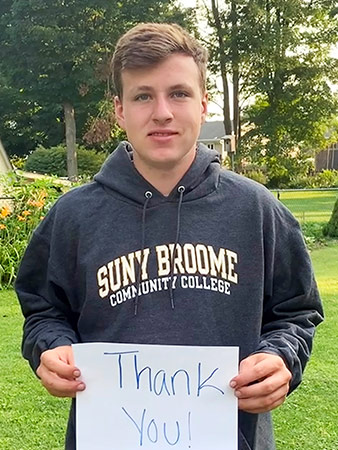 Andrew Rice wears a SUNY Broome sweatshirt and holds a thank you sign.