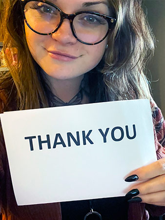 Arielle Conrad holds up a thank you sign and smiles.