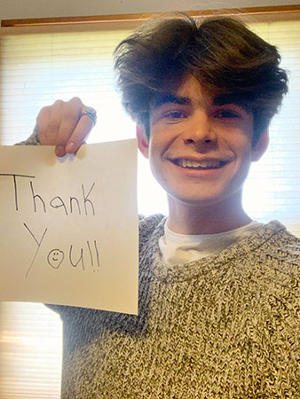 Liam holds up a thank you sign.
