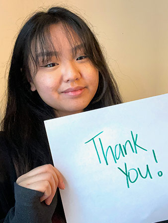 Mayna holds a thank you sign