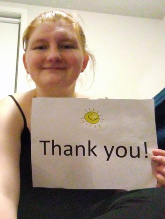 Kelsey holds a thank you sign