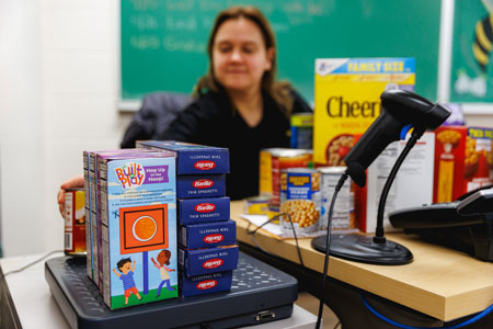 A volunteer weighs donated food items at The Hornet Hope Center checkout desk.